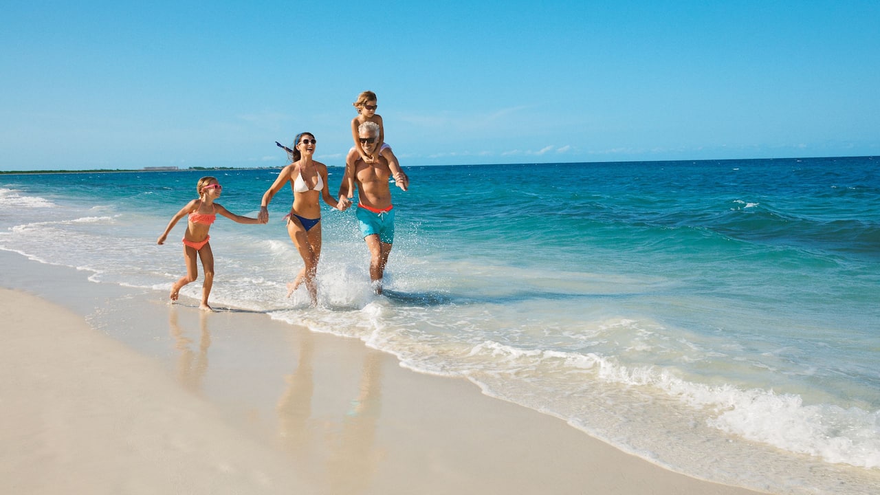 Familia caminando junto al mar en la playa de Dreams Playa Mujeres